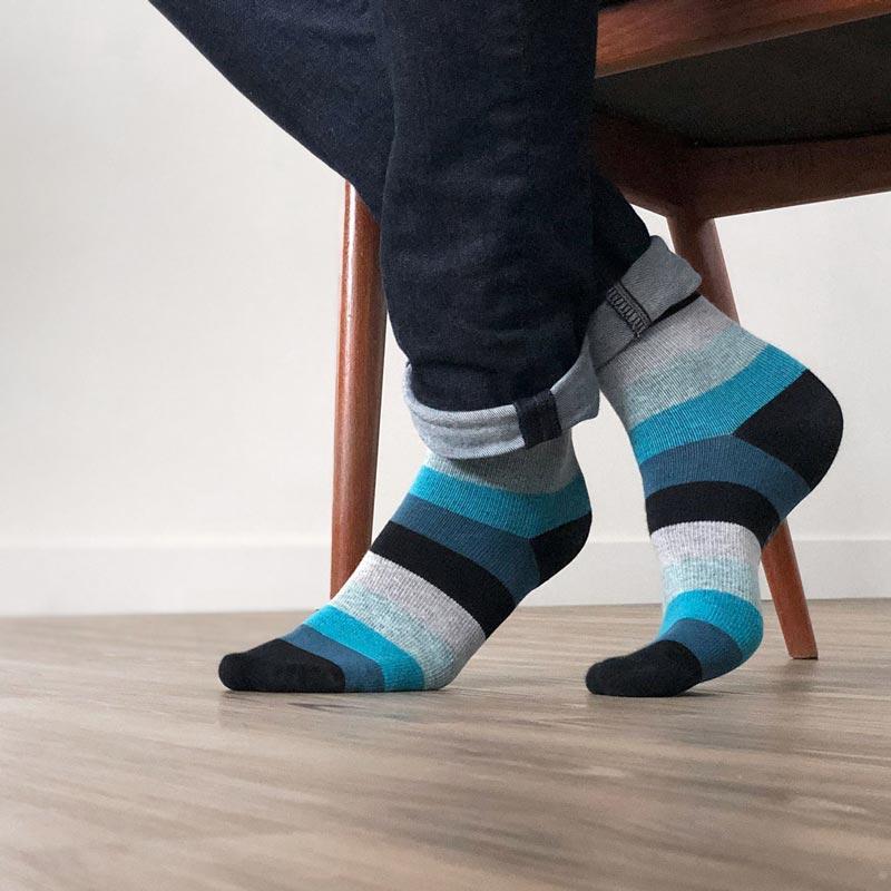 Man's feet sitting in chair with blue and black striped compression socks